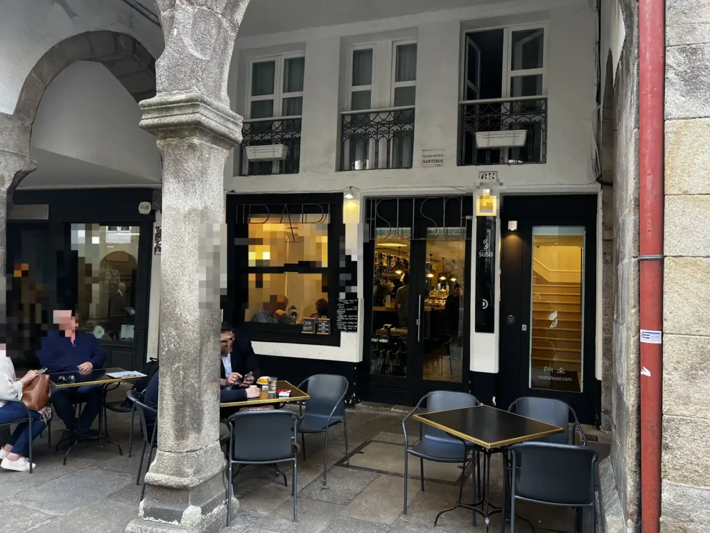 Fachada y terraza del Bar Suso en Santiago de Compostela, con clientes desayunando bajo los soportales del casco histórico