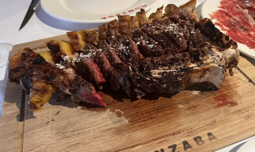 Chuletón de vaca madurada a la brasa, fileteado y con sal en escamas, servido en tabla de madera del Asador Gonzaba