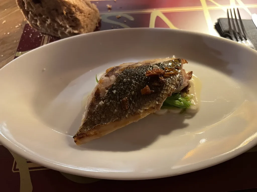 Lomo de lubina a la plancha con piel crujiente sobre cama de verduras, servido en Casa Marcelo, un sitio donde comer en Santiago de Compostela​​​​​​​​​​​​​​​​