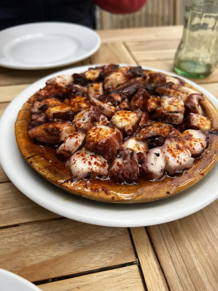Ración de pulpo a la gallega servido en tabla de madera con pimentón y aceite de oliva en el Gato Negro de Santiago de Compostela
