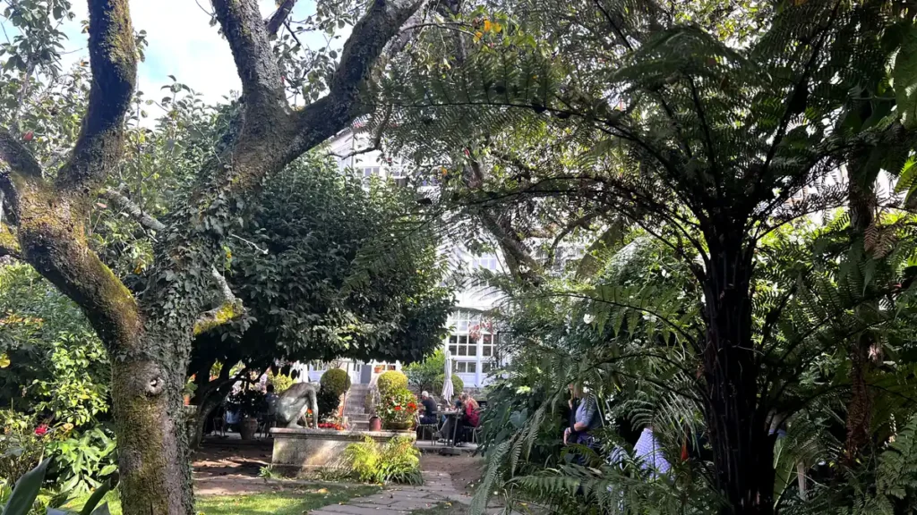 Terraza con jardín de un restaurante en Santiago de Compostela con vegetación frondosa y clientes comiendo al aire libre​​​​​​​​​​​​​​​​