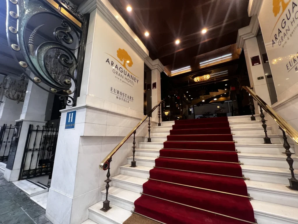 Entrada del Gran Hotel Araguaney Eurostars en Santiago de Compostela, con escalinata de mármol blanco, alfombra roja y señal de hotel de cinco estrellas