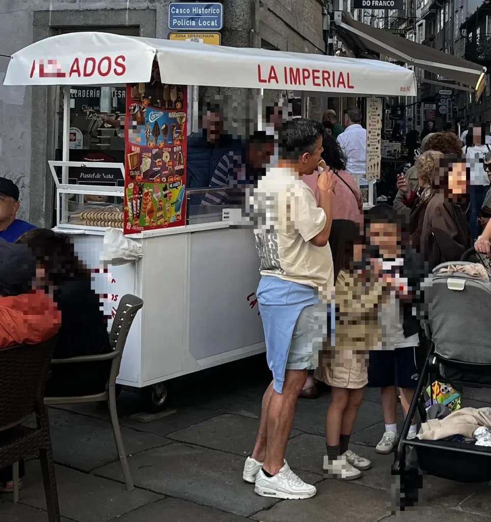 Carrito de helados artesanos La Imperial en el casco histórico de Santiago de Compostela, con turistas haciendo cola en Porta Faxeira