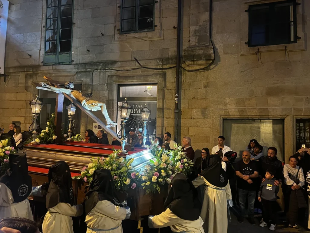 Encapuchados en procesión portando al Cristo crucificado en ca compostelana Rúa do Vilar