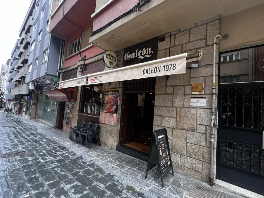 Fachada del bar restaurante Galeón 1978, una de la primeras hamburgueserías de Santiago de Compostela en la calle Alfredo Brañas de Santiago de Compostela, con toldo blanco, terraza recogida y carta de menús en la entrada