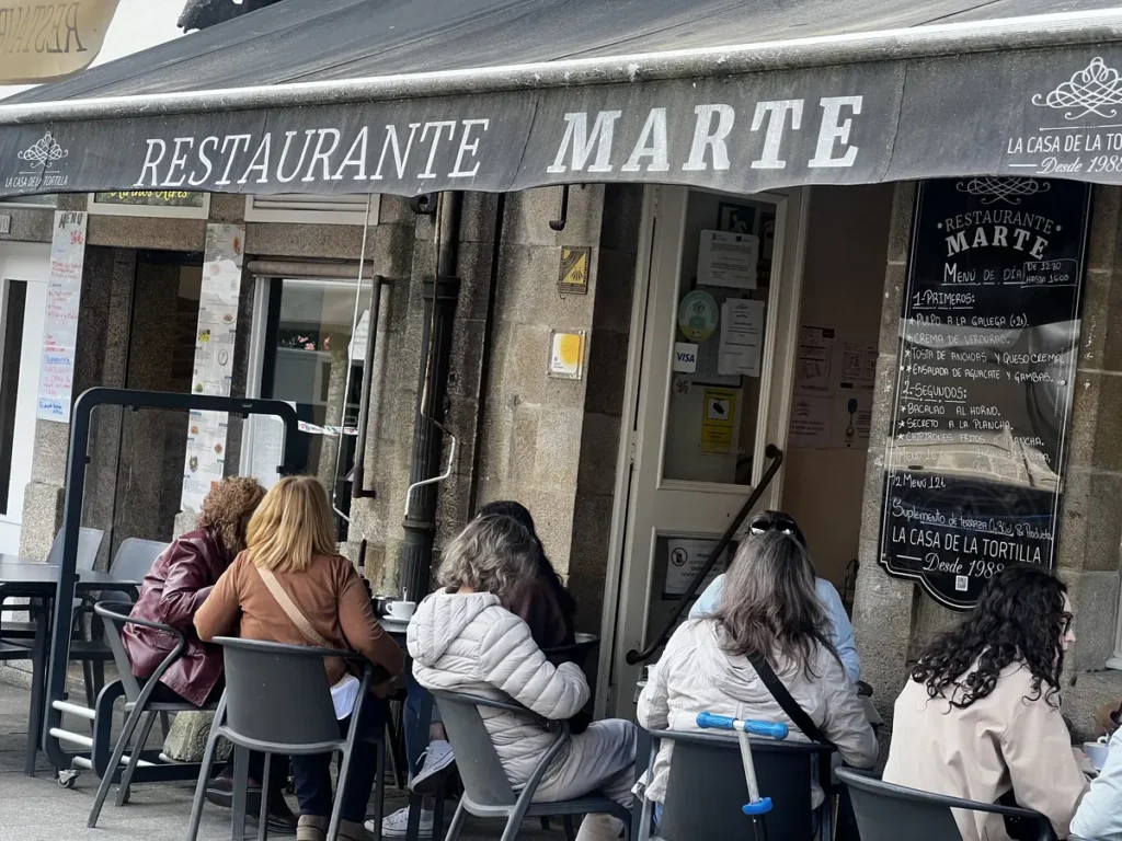 Terraza del Restaurante Marte en Santiago de Compostela, conocido como La Casa de la Tortilla desde 1988, con menú del día desde 16 € y opción de medio menú por 12 € y pizarra con pulpo a la gallega, bacalao al horno y chipirones. Un lugar donde comer barato en Santiago de Compostela.
