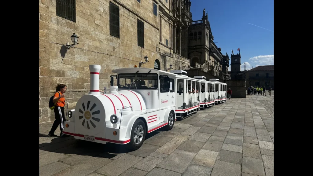 tours en Santiago de Compostela. Tren turístico blanco y rojo frente a la Catedral de Santiago de Compostela en la Plaza de las Platerías, uno de los tours más populares para visitar la ciudad compostelana.​​​​​​​​​​​​​​​​